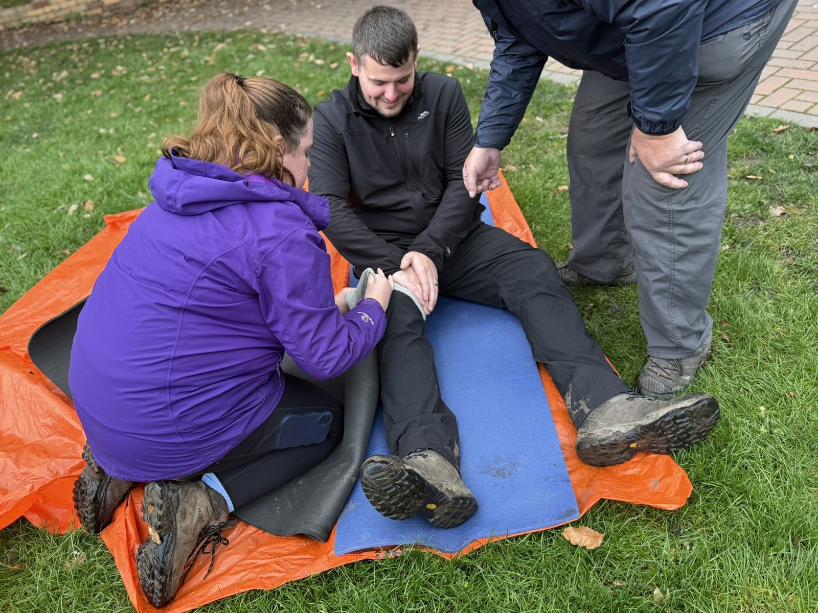 Humberside Scouts volunteers practising first aid outdoors on the grass, treating a casualty with a leg injury