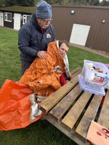 A Scout volunteer being wrapped in an orange survival bag during casualty care training